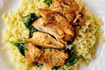 overhead shot of white plate with crock pot italian chicken on top of spinach and rice.