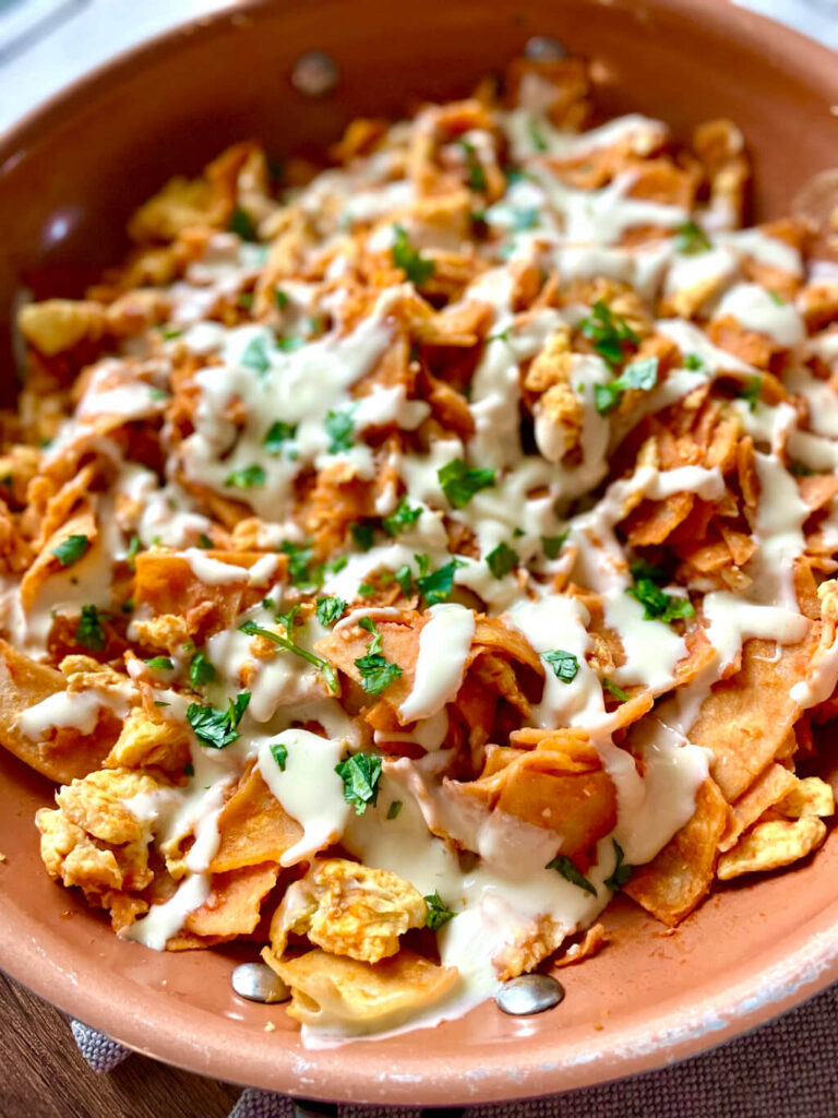 skillet with chilaquiles and eggs and white melting cheese