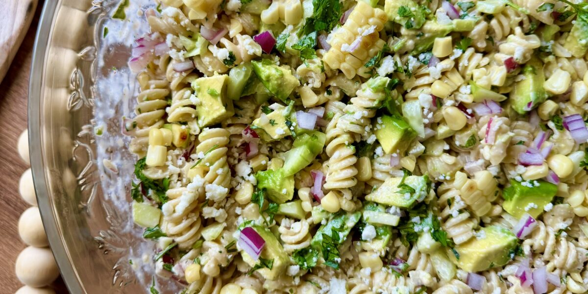 a large bowl with creamy cilantro lime pasta salad with avocados