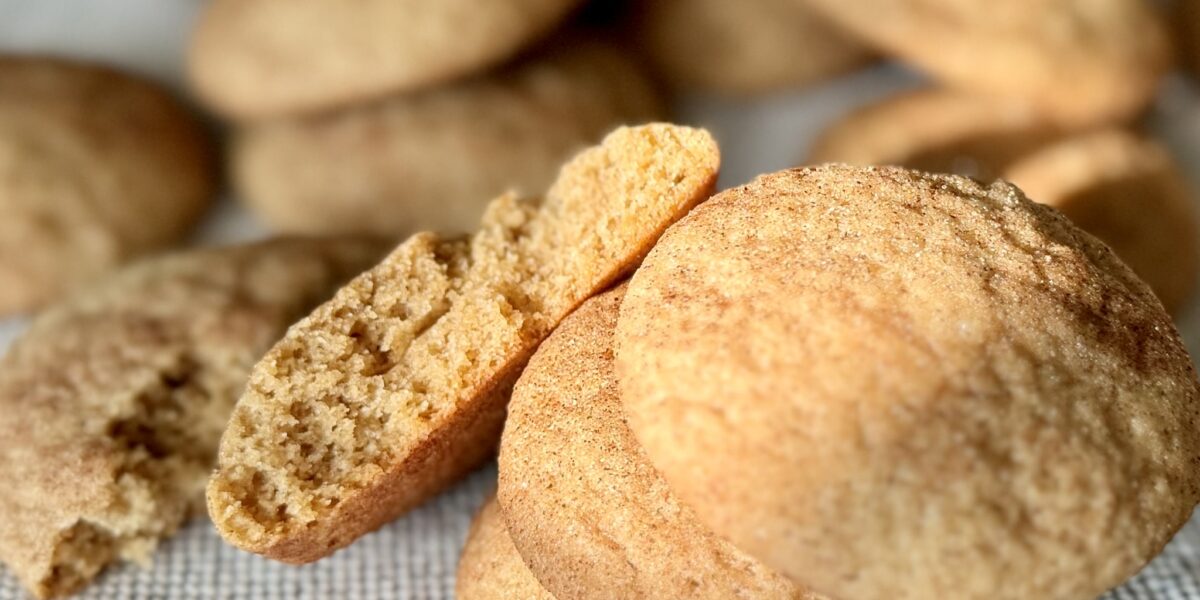 A stack of churro cookies with one broken open to show the softness inside.