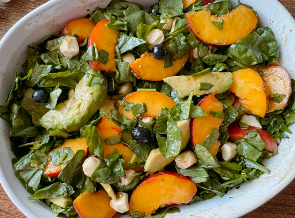 a bowl of peach salad with the ingredients tossed together