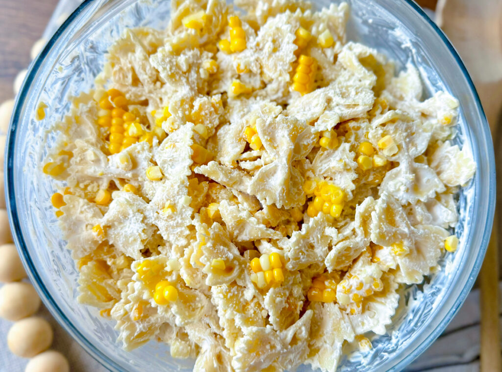 large, clear glass bowl with corn pasta salad in it