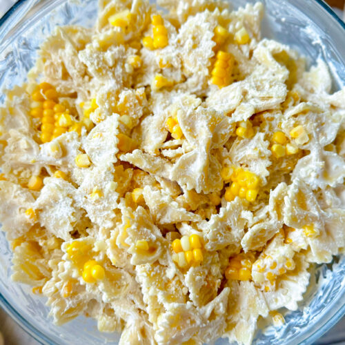 large, clear glass bowl with corn pasta salad in it