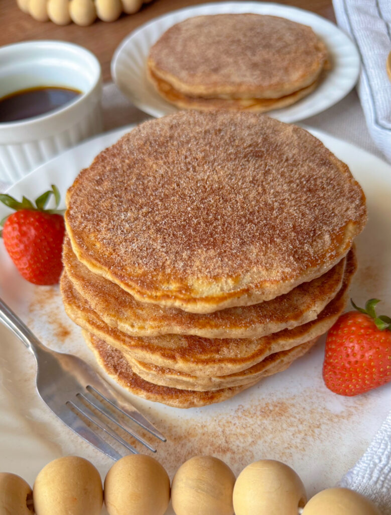 Stack of fluffy churro pancakes covered in cinnamon sugar coating