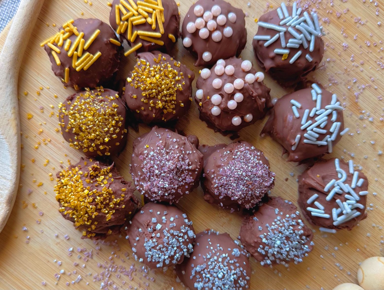 no bake chocolate cheesecake balls on wooden tray with colorful sprinkles