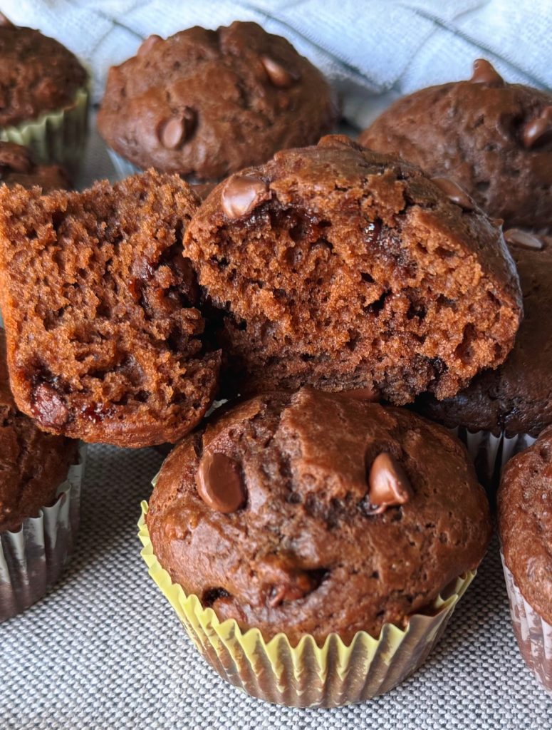 Close-up of a chocolate Greek yogurt muffin cut in half, showing the soft, moist interior and melted chocolate chips.