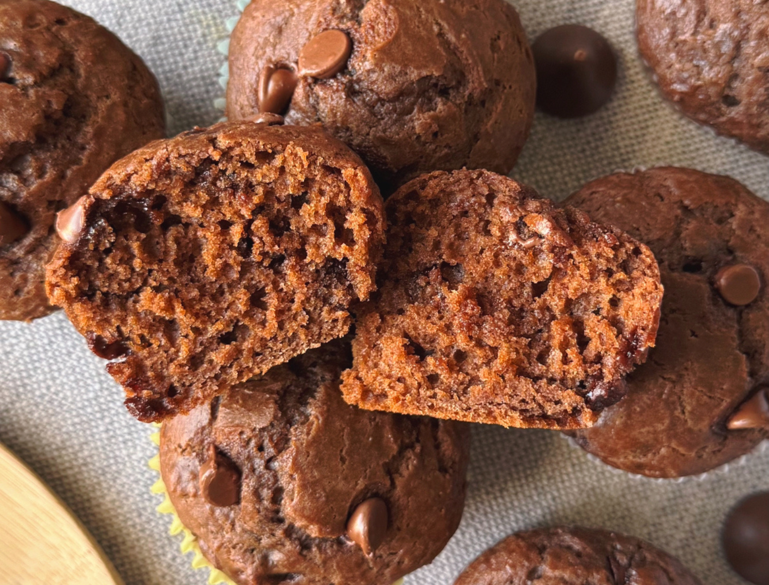 overhead shot of double chocolate greek yogurt muffins with one cut in half to show soft texture inside