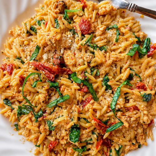 plate of marry me orzo with ground turkey, red sun-dried tomatoes and bright green spinach