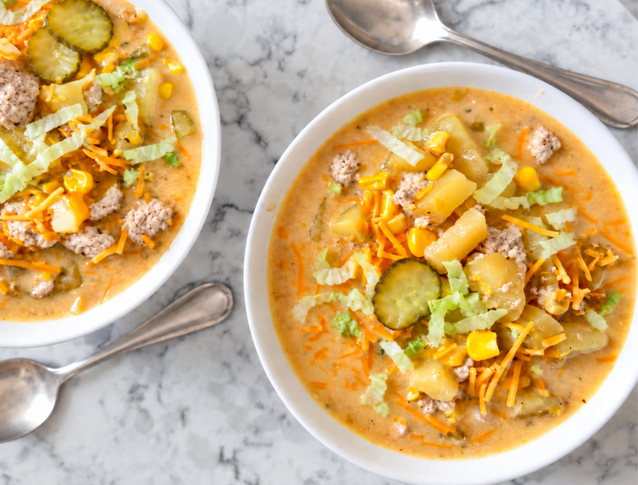 two bowls on a white marble countertop with turkey cheeseburger soup in each one